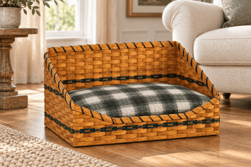 Large woven pet bed basket with Hunter Green accents and a plaid cushion beside an armchair. Cushion shown is optional.