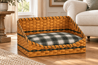 Large woven pet bed basket with Hunter Green accents and a plaid cushion beside an armchair. Cushion shown is optional.