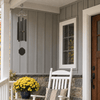 Melody of the Heart textured copper wind chime beside a white rocking chair on a gray porch.