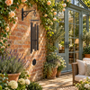 Victory Bells of Jericho textured copper wind chime beside a brick conservatory with blue-green glazing and apricot roses.