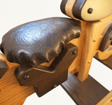 Close-up of the rocking motorcycle's cushioned seat and wooden side support.